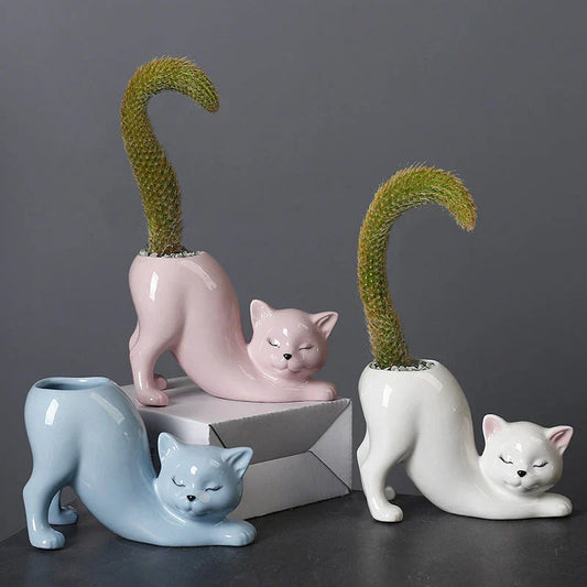 A white ceramic flower pot with a playful cartoon cat design and a functional tail element, perfect for desktops and small spaces.