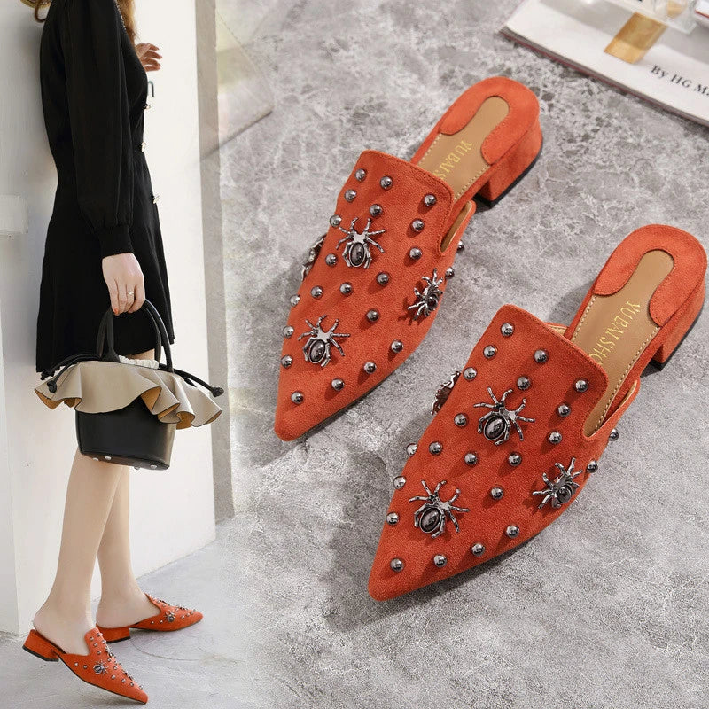 A pair of flat-bottomed, lazy half-slipper style sandals in a sleek, minimalist design with metal accents