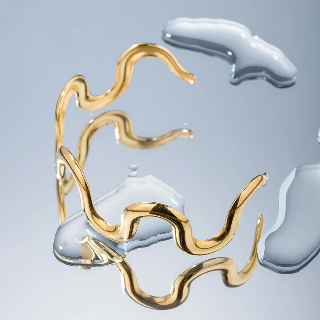 Elegant 18K gold-plated stainless steel wave bracelet and necklace set for women, showcasing a unique contemporary design with adjustable drawstring closure