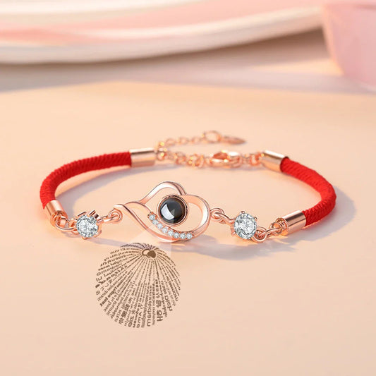 A rose gold or platinum plated copper charm bracelet featuring the phrase 'I Love You' inscribed in 100 languages.
