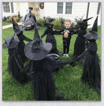 Three tall, black-robed witch figures with faceless glowing heads, standing together and holding hands, creating a spooky outdoor Halloween display