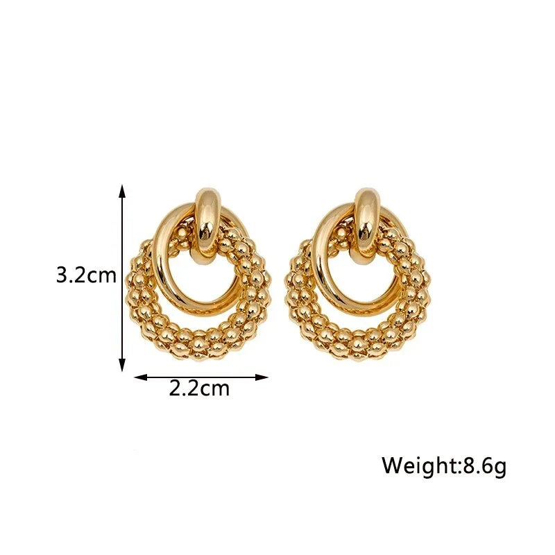 Exquisite gold twist dangle earrings with an intricate geometric design, a bold statement of modern elegance for fashion-forward women.