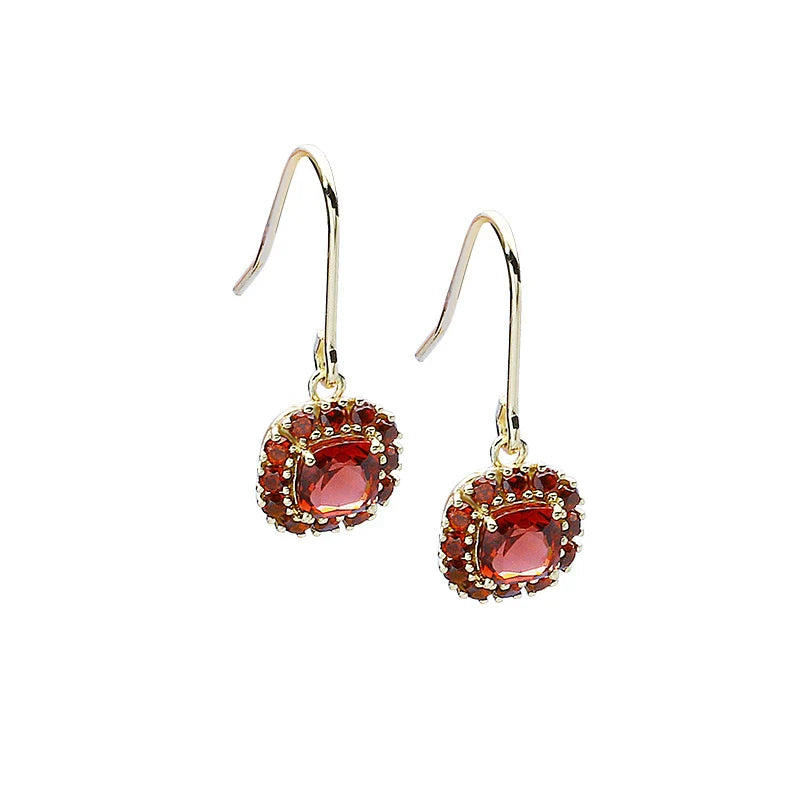 A pair of elegant red pomegranate-inspired earrings with a silver finish and geometric design, showcasing British style and sophistication.