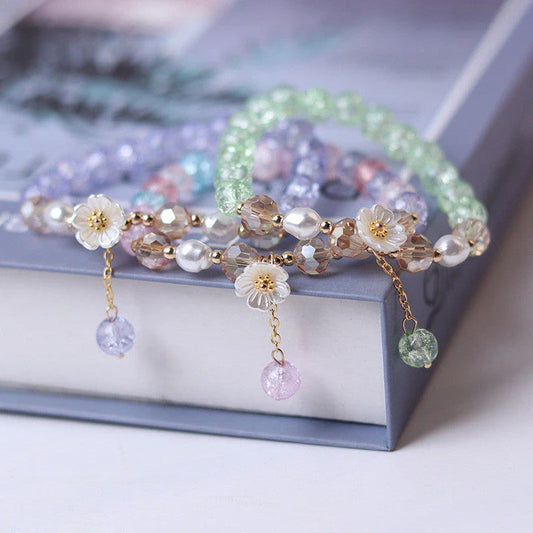 Elegant beaded bracelet with a white flower charm, vibrant purple crystal beads, and an adjustable design for a comfortable fit
