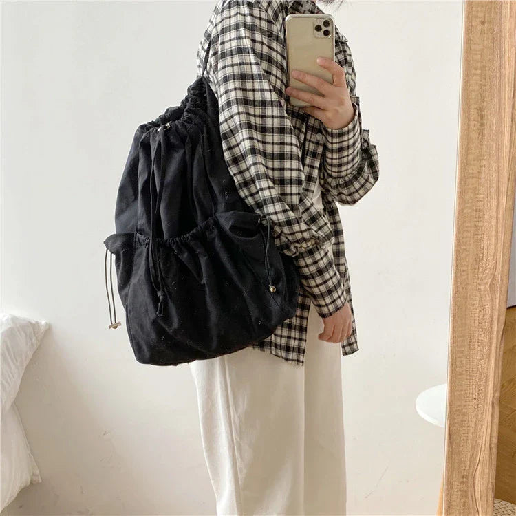 A stylish drawstring bucket bag in white, black, or brown colour options, featuring a spacious interior and adjustable closure for modern British women.