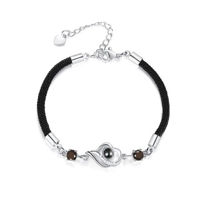 A rose gold or platinum plated copper charm bracelet featuring the phrase 'I Love You' inscribed in 100 languages.
