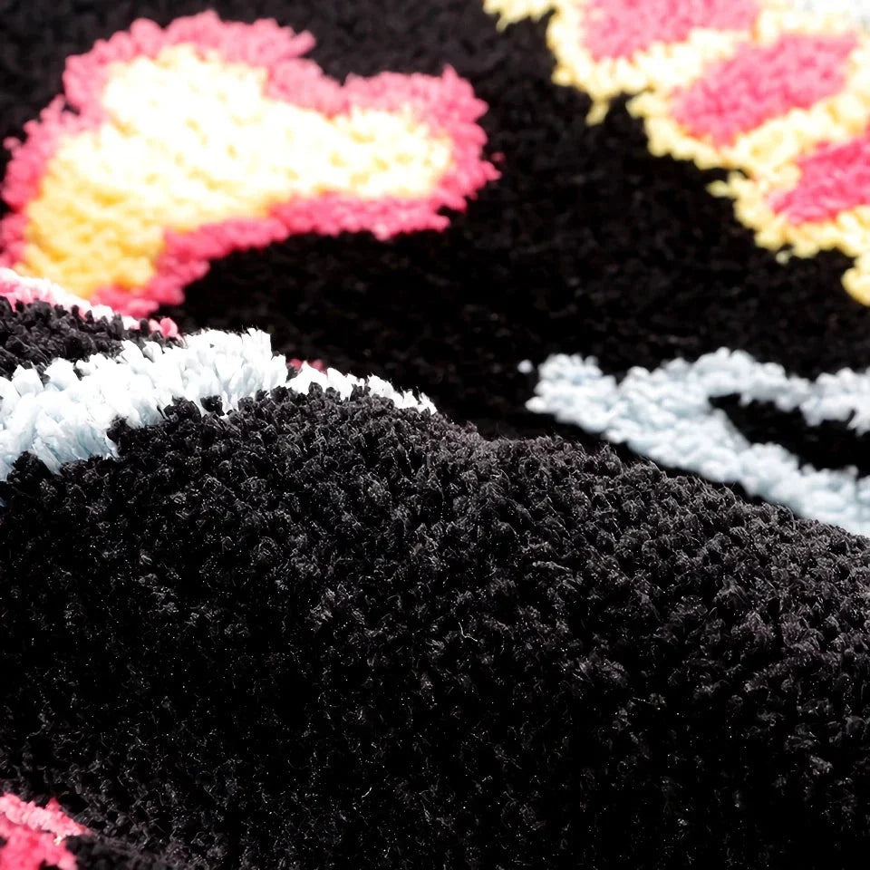 A stylish, black and pink skull-patterned area rug with an irregular, funky design for a modern living room or bedroom