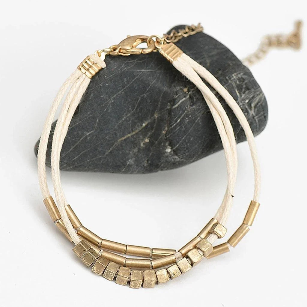 Stylish multilayered bracelet with beige leather ropes and gold-coloured beads, a modern and sophisticated accessory