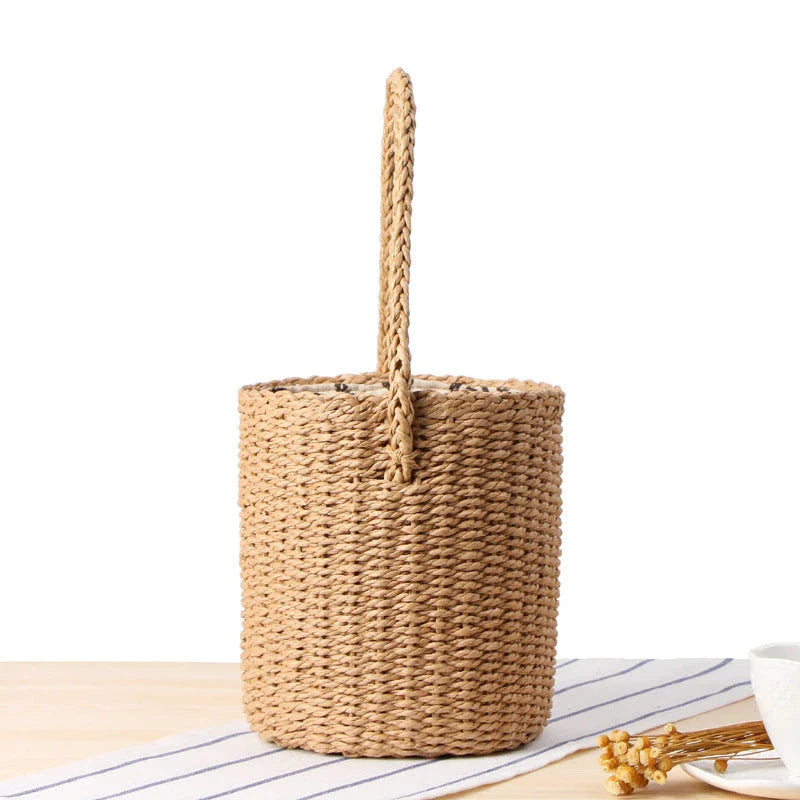 Elegant hand-crafted straw bucket bag in camel or beige, featuring a compact and lightweight design for versatile British summer style