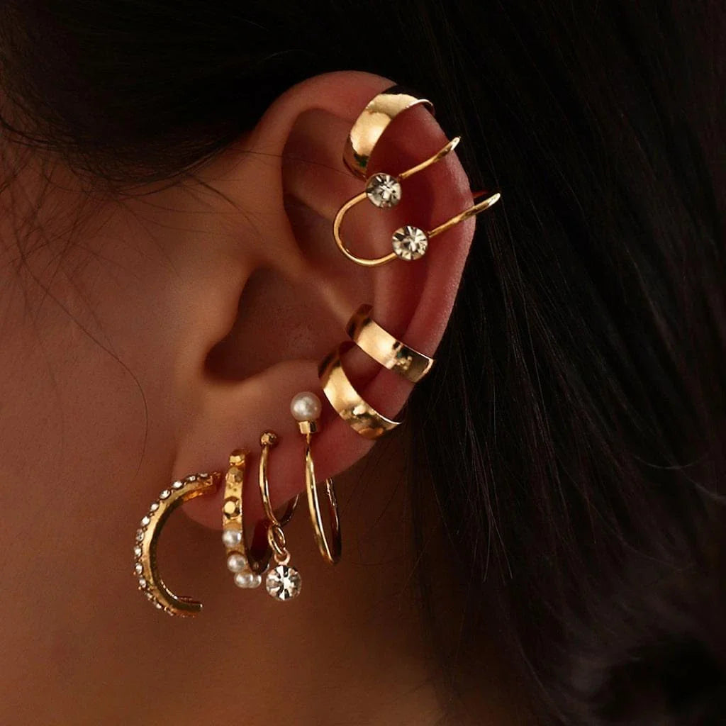 A set of 8 sophisticated gold-toned pearl stud earrings with unique, eye-catching designs