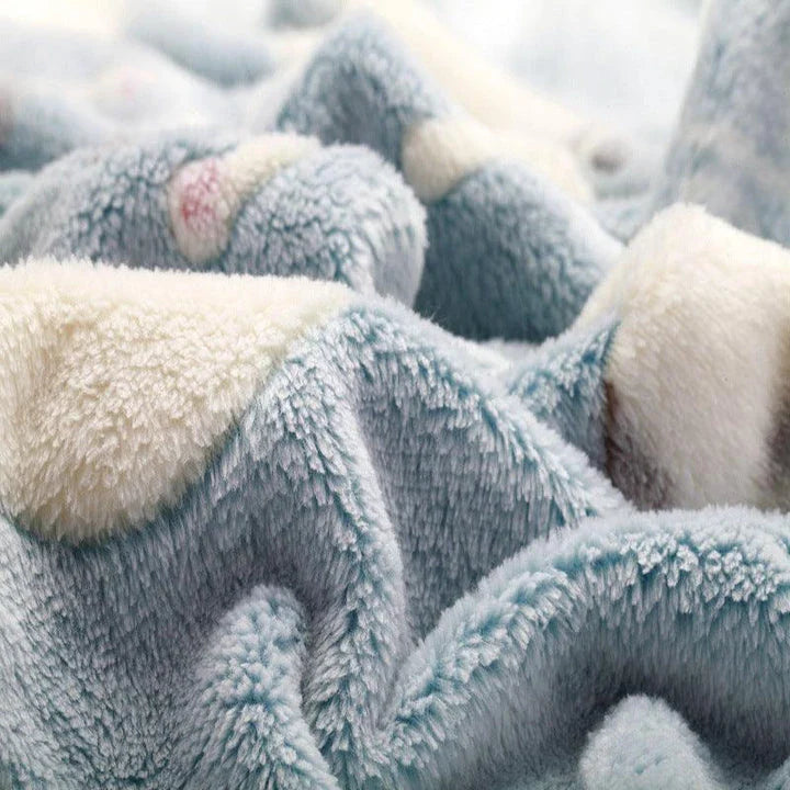 A large, soft, and cosy fleece blanket in a light blue colour, perfect for snuggling up on a bed or sofa
