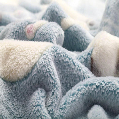 A large, soft, and cosy fleece blanket in a light blue colour, perfect for snuggling up on a bed or sofa