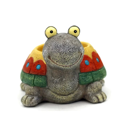 A charming, hand-painted resin planter in the shape of a cartoon turtle, perfect for displaying succulents, cacti, and other small plants.