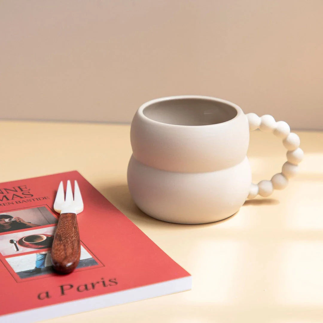 Handmade ceramic mug in beige and blue Nordic-inspired design, with a comfortable handle for enjoying hot or cold beverages.