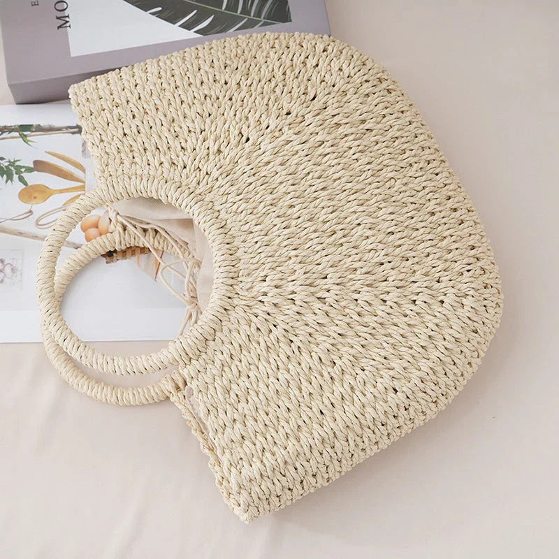 Premium handwoven straw beach tote with a casual half-moon shape and secure string closure, perfect for summer outings
