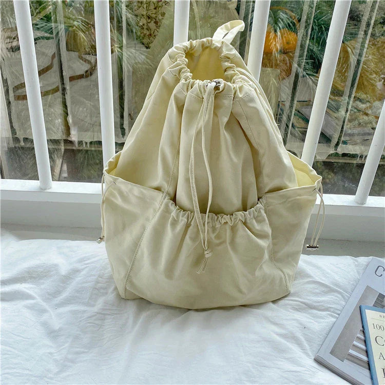 A stylish drawstring bucket bag in white, black, or brown colour options, featuring a spacious interior and adjustable closure for modern British women.