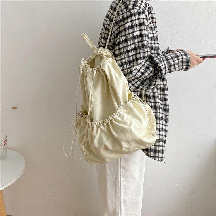 A stylish drawstring bucket bag in white, black, or brown colour options, featuring a spacious interior and adjustable closure for modern British women.