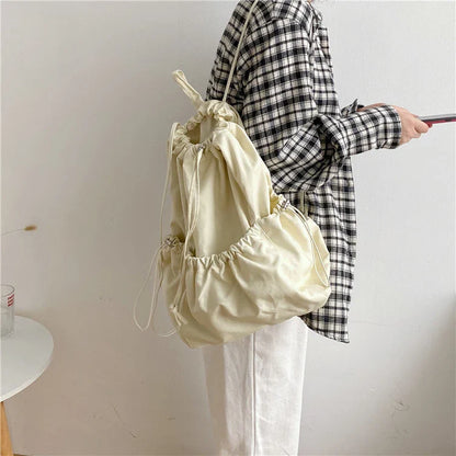 A stylish drawstring bucket bag in white, black, or brown colour options, featuring a spacious interior and adjustable closure for modern British women.