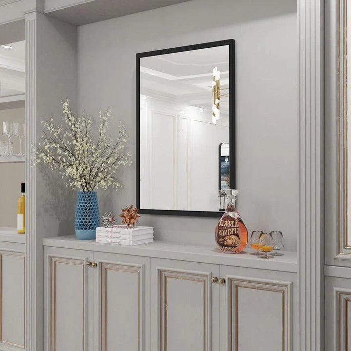 Sophisticated black metal framed wall mirror with rounded corners, reflecting a bright and spacious room