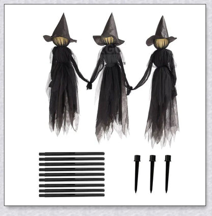 Three tall, black-robed witch figures with faceless glowing heads, standing together and holding hands, creating a spooky outdoor Halloween display