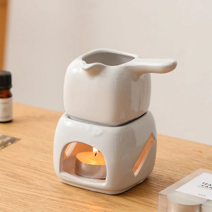 Elegant ceramic candle holder and tea warmer set in a classic square design with a wooden handle