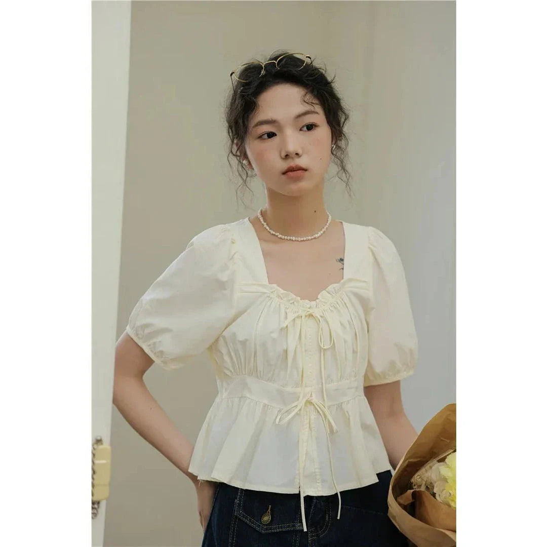 Elegant vintage-inspired blouse with square neckline, puff sleeves, and lace-up details for a timeless, sophisticated look