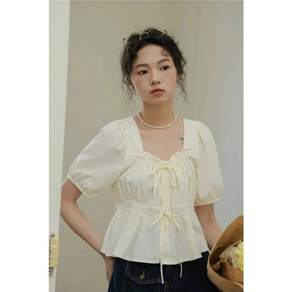 Elegant vintage-inspired blouse with square neckline, puff sleeves, and lace-up details for a timeless, sophisticated look