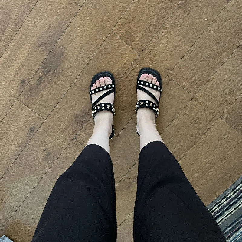 Black flat sandals with orange accents, inspired by the Roman Holiday style, suitable for women