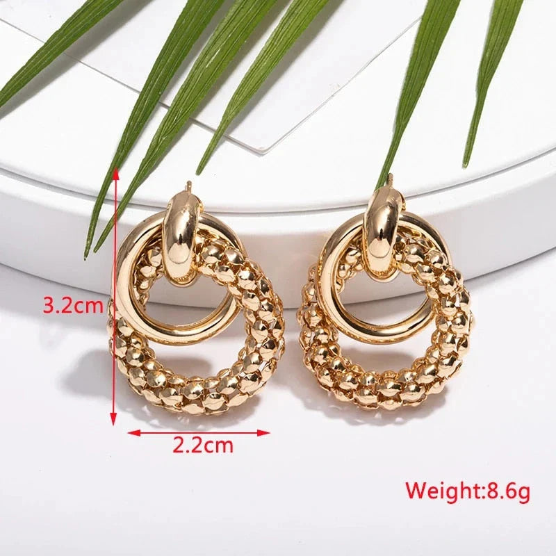 Exquisite gold twist dangle earrings with an intricate geometric design, a bold statement of modern elegance for fashion-forward women.