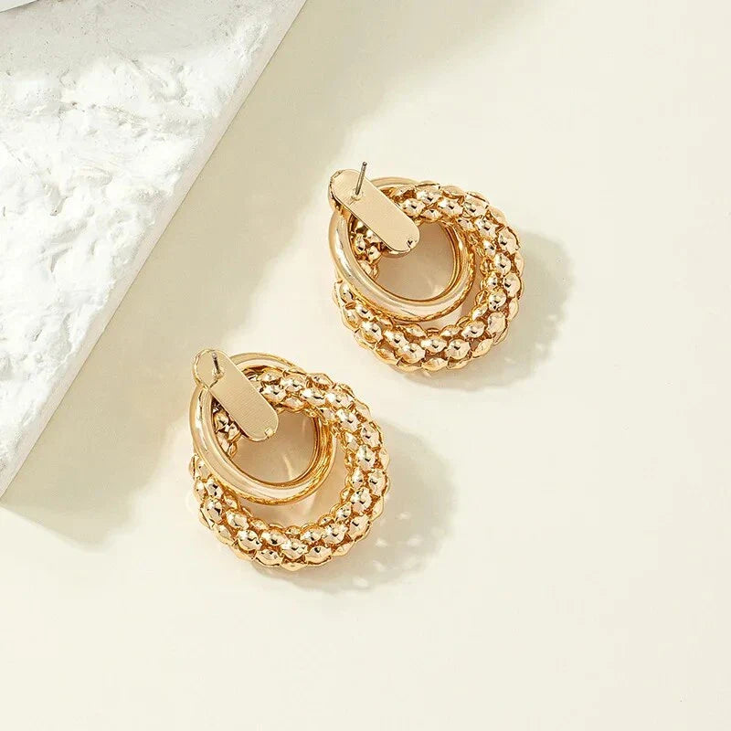 Exquisite gold twist dangle earrings with an intricate geometric design, a bold statement of modern elegance for fashion-forward women.