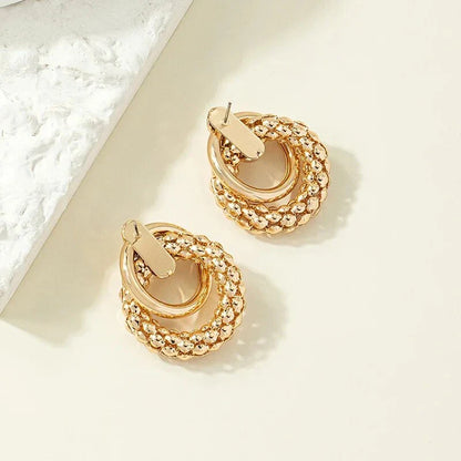 Exquisite gold twist dangle earrings with an intricate geometric design, a bold statement of modern elegance for fashion-forward women.