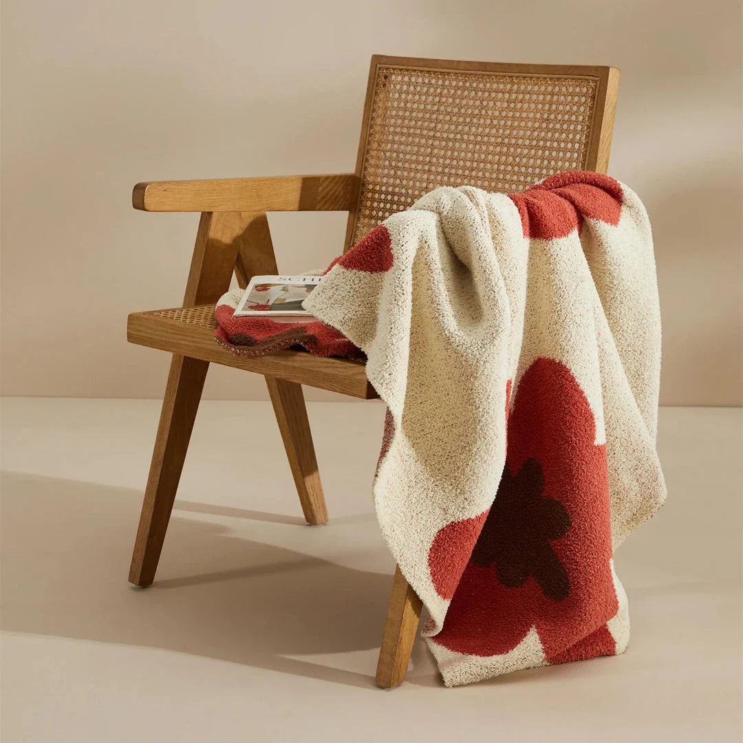 Cosy floral knitted throw blanket in red, grey, and orange colours for year-round comfort and style