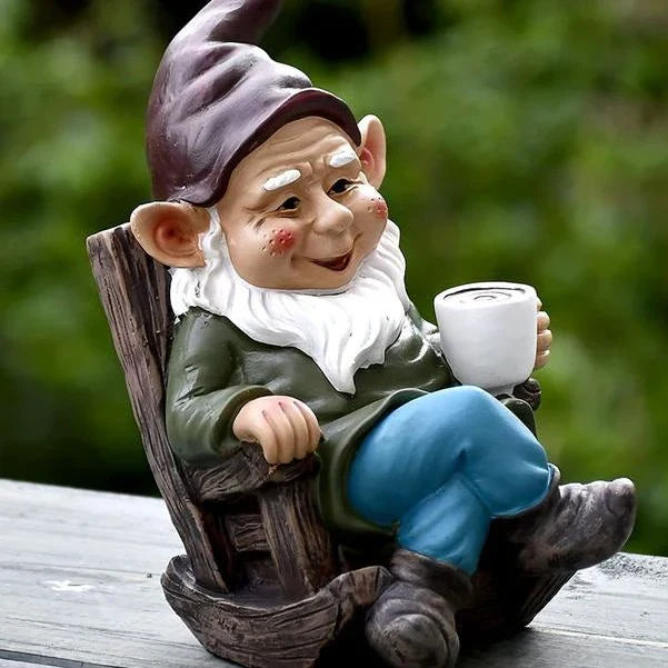 A charming garden gnome ornament made of durable resin, sitting in a rocking chair and sipping tea, adding whimsical personality to an outdoor space