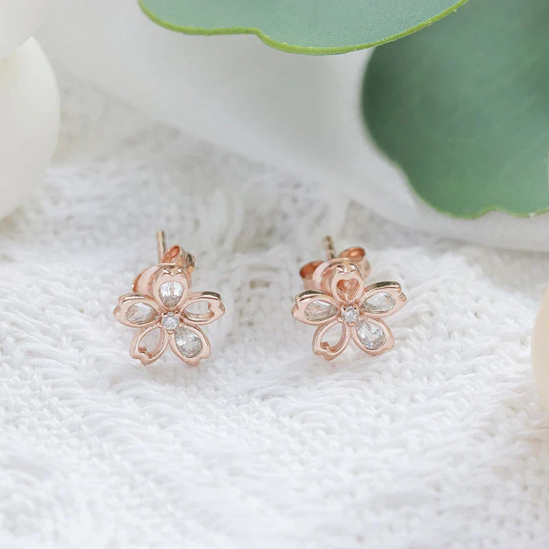 Pair of elegant zircon cherry blossom earrings in skin colour, featuring a delicate floral design and sparkling stones