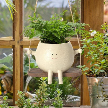 A white hanging planter with a charming, smiling child's face design, perfect for indoor or outdoor use.