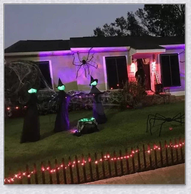 Three tall, black-robed witch figures with faceless glowing heads, standing together and holding hands, creating a spooky outdoor Halloween display
