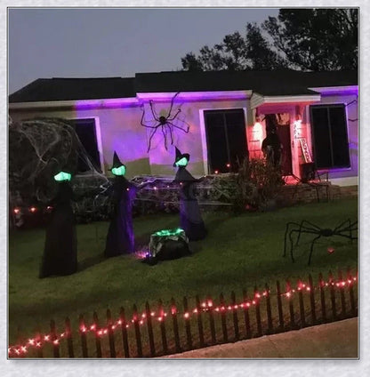 Three tall, black-robed witch figures with faceless glowing heads, standing together and holding hands, creating a spooky outdoor Halloween display
