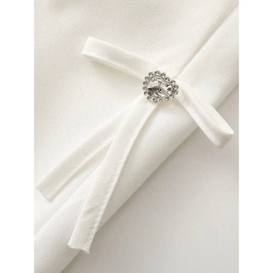 Stylish women's white blazer with a sparkling diamond bow accent, designed for fashion-forward British women