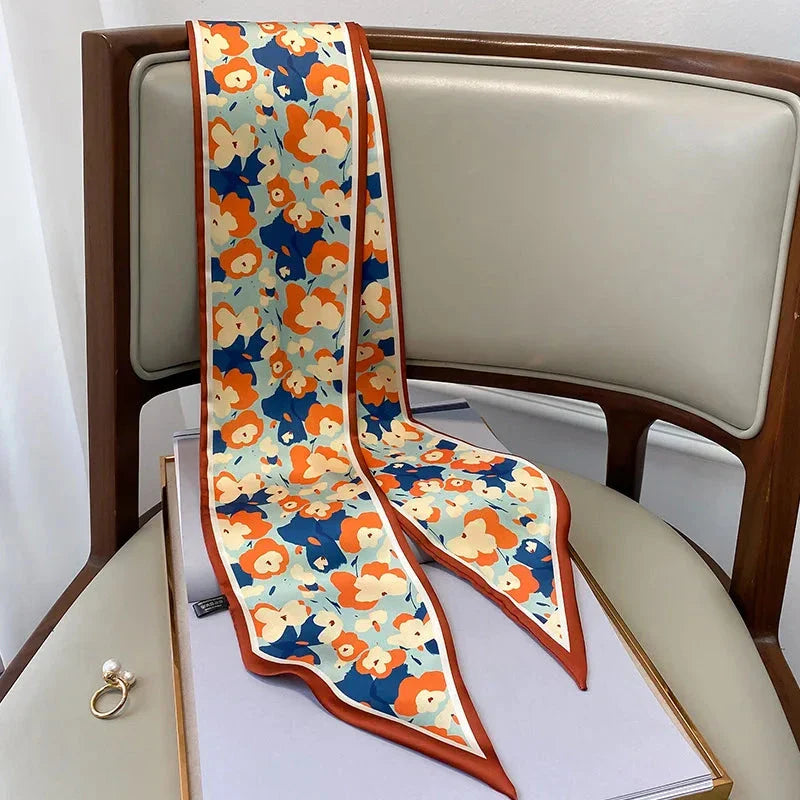 A vibrant floral-patterned silk-feel long scarf that can be worn as a neck accessory, hair tie, or wrist adornment for all occasions.