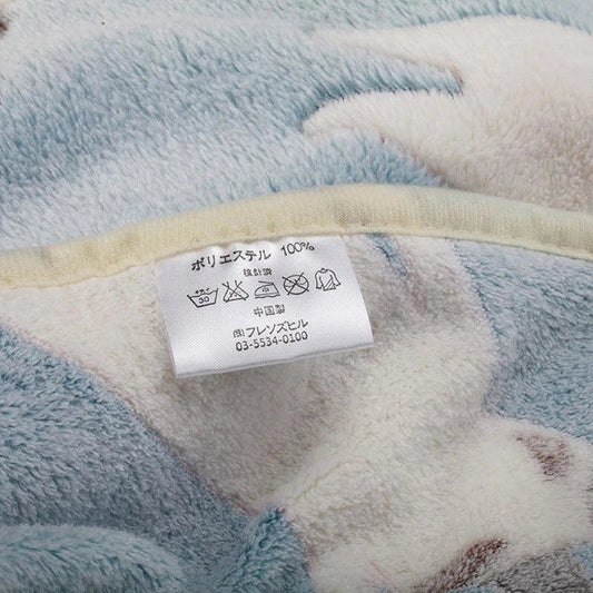 A large, soft, and cosy fleece blanket in a light blue colour, perfect for snuggling up on a bed or sofa