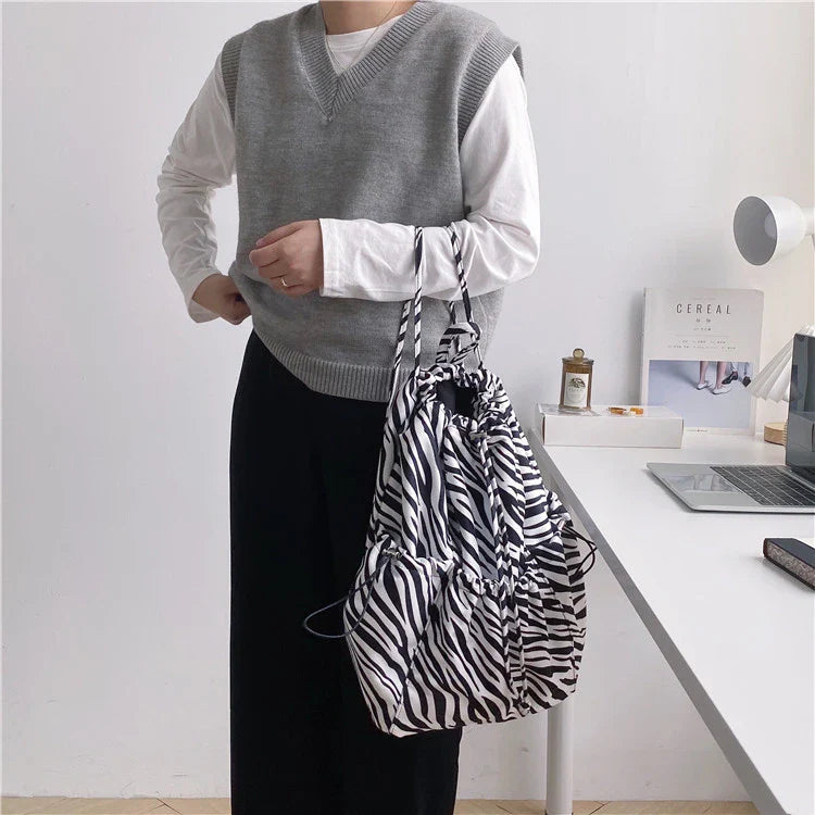 A stylish drawstring bucket bag in white, black, or brown colour options, featuring a spacious interior and adjustable closure for modern British women.
