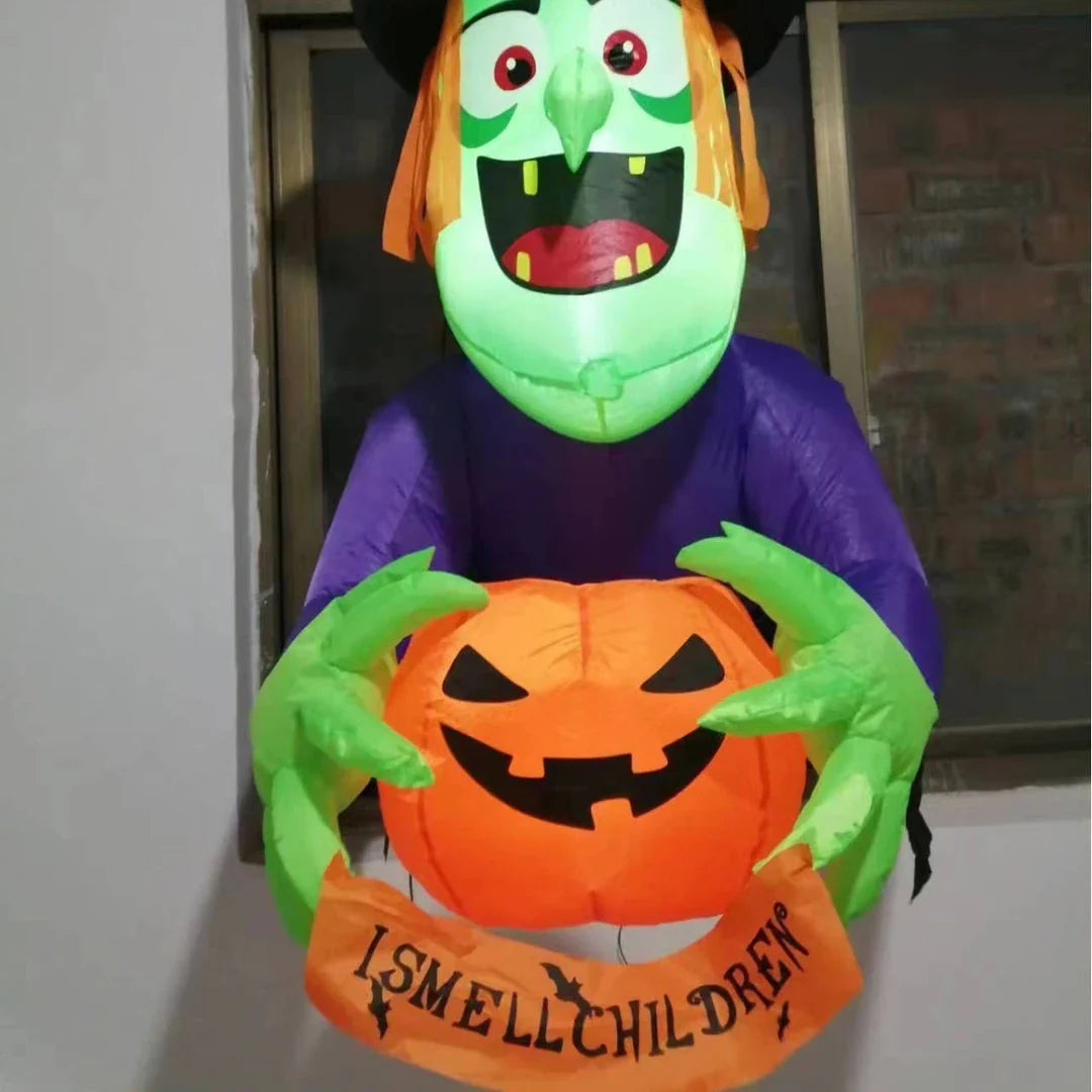Inflatable Halloween witch decoration holding a spooky pumpkin, set up in a garden or outdoor space