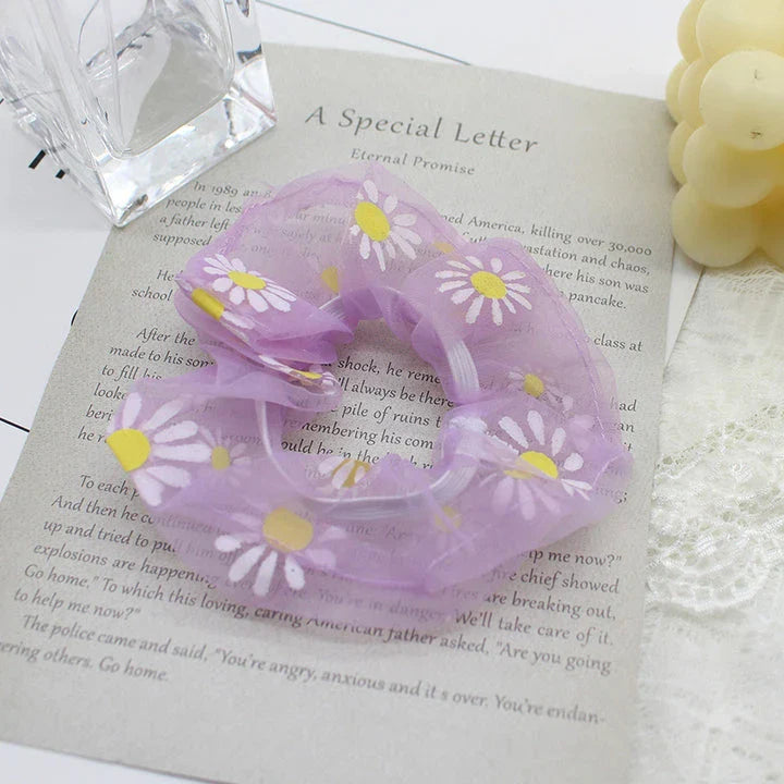 A pair of white hair bands with vibrant, hand-embroidered daisy patterns, providing a stylish and comfortable accessory.